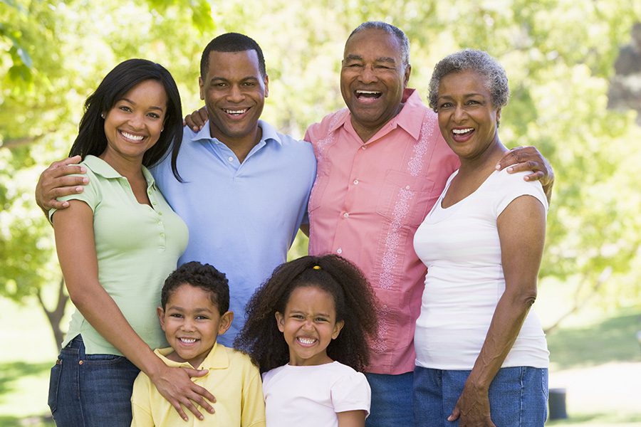 About Our Agency - A Group Shot of a Family of Three Generations Embracing Each Other and Smiling at a Park